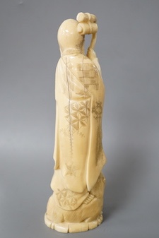 A Japanese carved walrus ivory figure of Fukurokuju, early 20th century,standing on the back of a tiger holding his staff, inset red seal mark to base, height 22cm